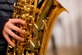 Hand auf den Klappen eines goldglänzenden Saxofons, Nahaufnahme