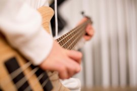 Nahaufnahme von Händen beim Spielen eines E-Basses