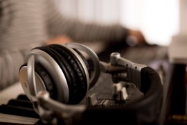 Grosse Kopfhörer auf einem Controller mit Reglern, dahinter unscharf eine Person