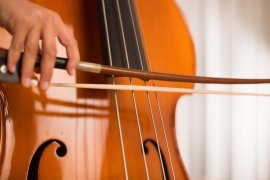 Nahaufnahme: Eine Hand führt den Bogen über die Saiten eines Kontrabasses