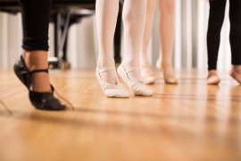 Nahaufnahme tanzender Füsse in Ballettschuhen und barfuss auf einem Parkettboden