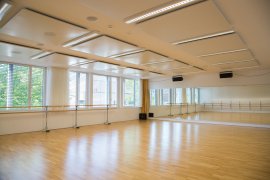 Heller Tanzsaal mit Parkettboden, Ballettstangen und Spiegelwand