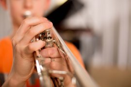 Kind spielt Trompete, Nahaufnahme von Hand und Ventilen